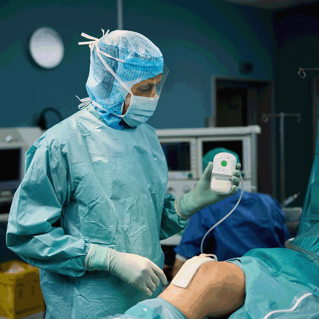 A photo of a surgeon holding a pump connected to a wound dressing. 
